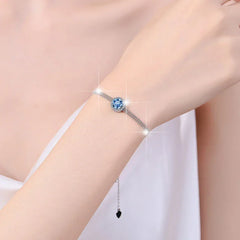 Silver bracelet with a blue gemstone on a person's wrist against a white background