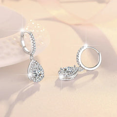 Pair of silver earrings with clear gemstones on a soft pink background