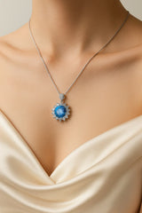 Necklace with a blue pendant on a mannequin wearing a cream dress.