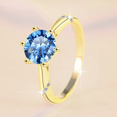 Gold ring with a blue gemstone on a beige background