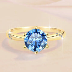 Gold ring with a blue gemstone on a beige background