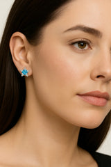Close-up of a woman wearing a blue gemstone earring against a neutral background