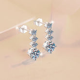 Pair of silver earrings with clear gemstones on a beige background