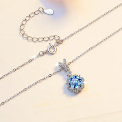 Silver necklace with a blue gemstone pendant on a light background