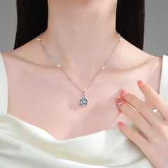 Silver necklace with a heart-shaped pendant worn by a model, with a hand touching the necklace.