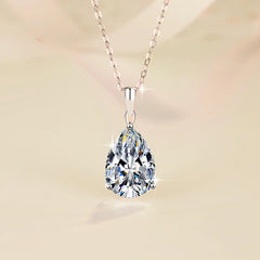 Teardrop-shaped diamond pendant on a chain against a soft gradient background