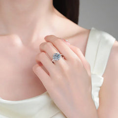 Close-up of a hand wearing a silver ring with a diamond on a neutral background