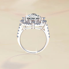 Silver ring with a large central diamond and smaller diamonds on the band against a beige background