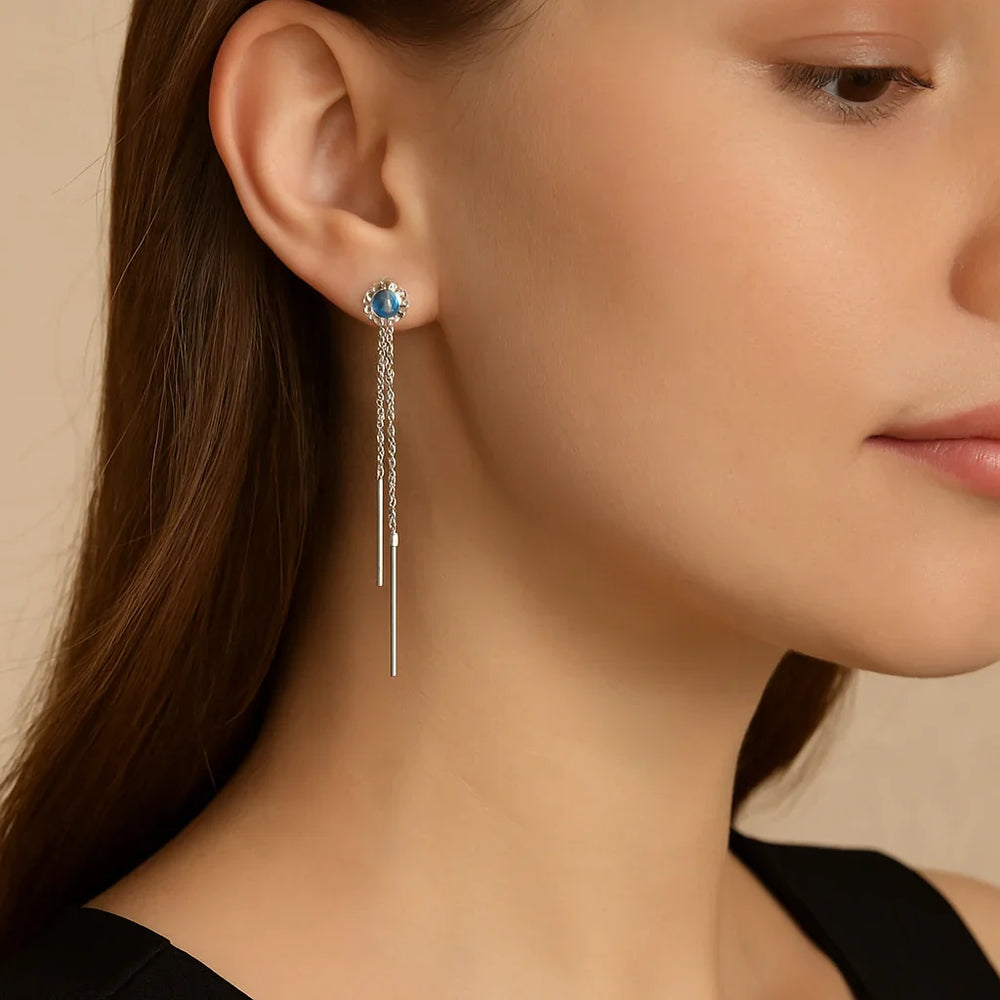 Close-up of woman wearing blue moissanite sterling silver chain drop earrings