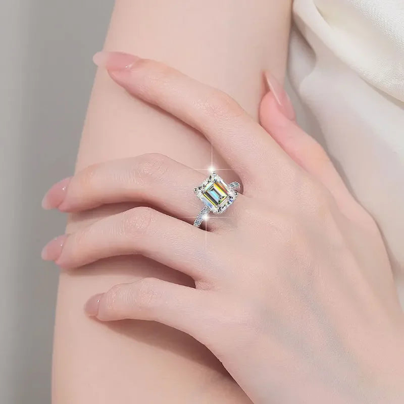 Close-up of hand wearing a sparkling emerald-cut diamond ring with a silver band