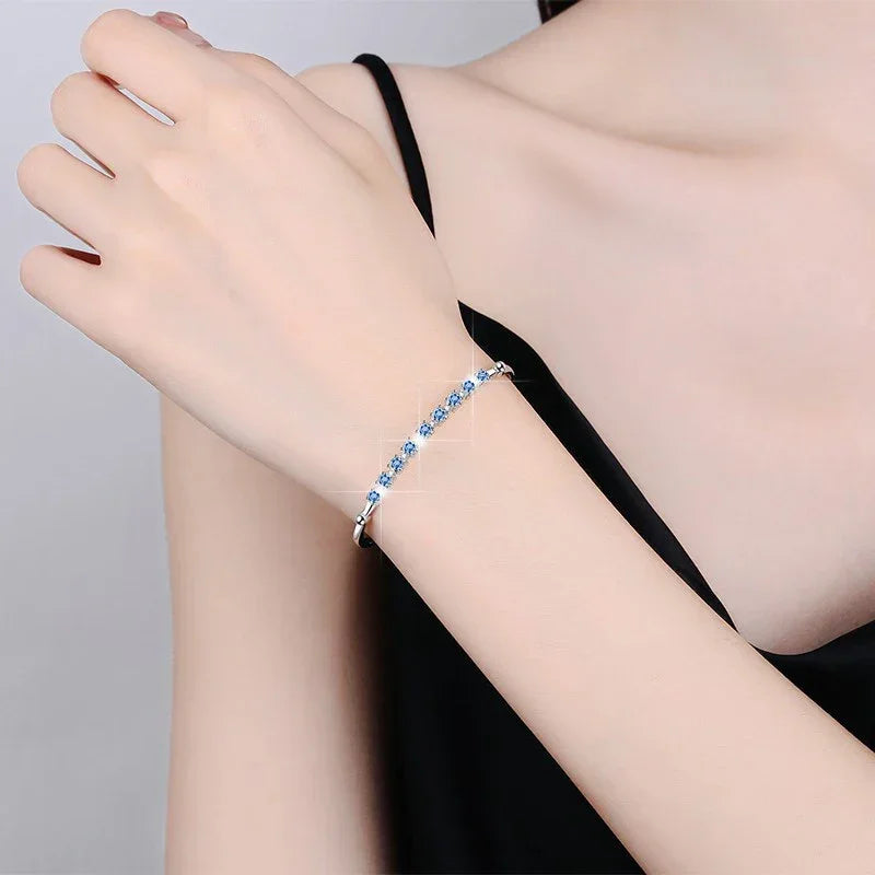 Hand wearing a blue beaded bracelet on a plain background