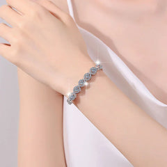 Silver bracelet with clear stones on a wrist against a soft pink background