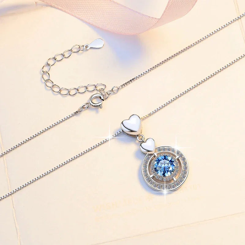 Necklace with a heart-shaped pendant and blue gemstone on a light background