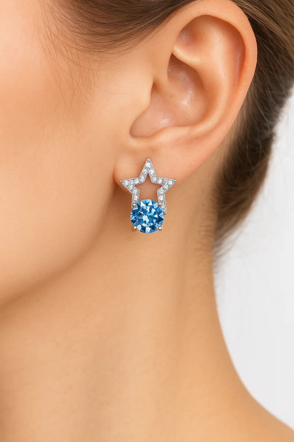 Star-shaped earrings with blue gemstones worn by a person