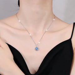Necklace with a blue pendant worn by a person in a black top.