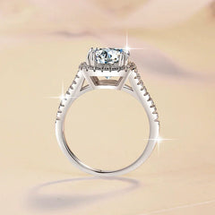 Silver ring with a large diamond and smaller diamonds on the band against a beige background