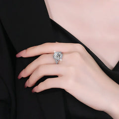 Close-up of a hand wearing a silver ring with a diamond on a black background