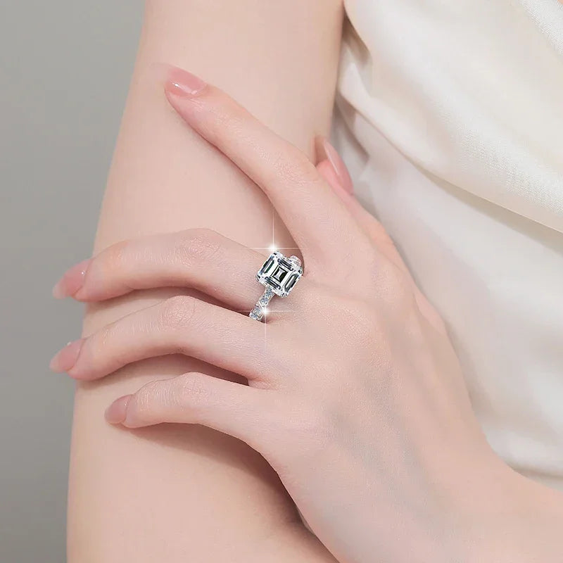 Silver ring with a gemstone on a person's finger against a neutral background