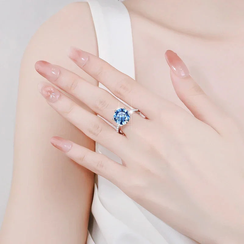 Close-up of a hand wearing a ring with a blue gemstone on a light background