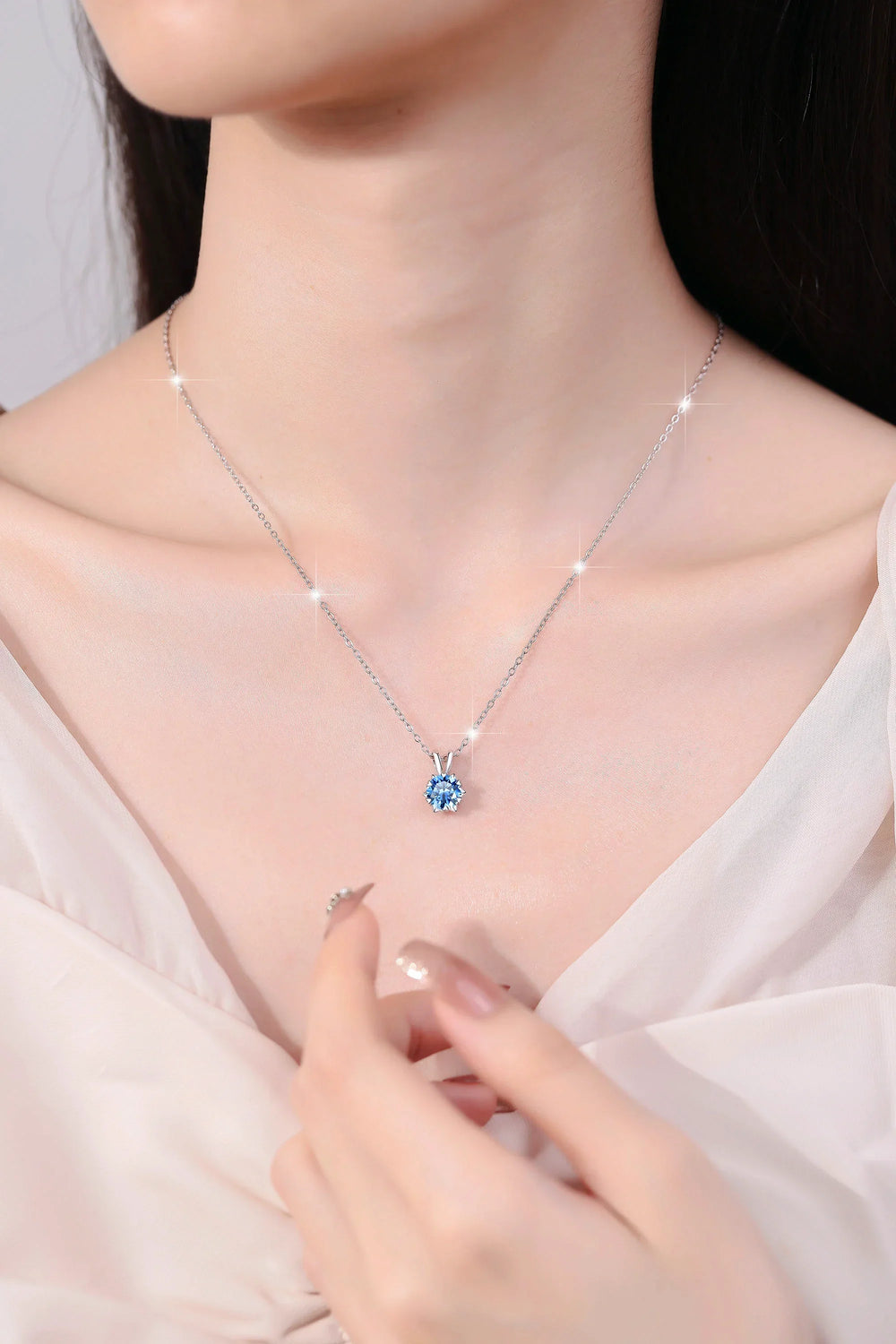 Necklace with a blue gemstone worn by a person, highlighting the jewelry's design.