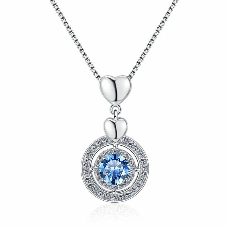 Silver necklace with a heart pendant and blue gemstone on a white background