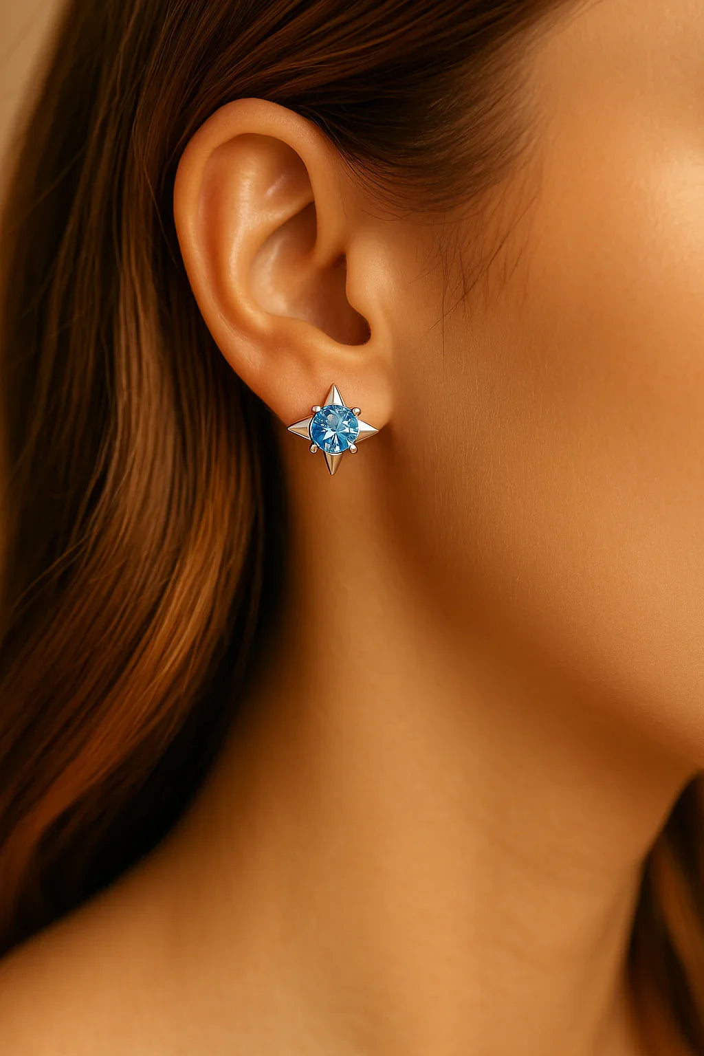 Close-up of an ear wearing a blue gemstone earring with a blurred background