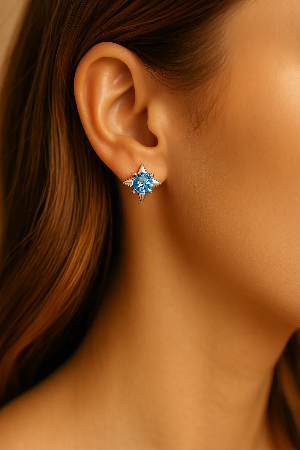 Close-up of an ear wearing a blue gemstone earring with a blurred background