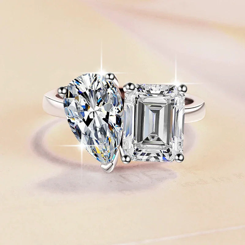 Diamond ring with pear-shaped and emerald-cut diamonds on a beige background