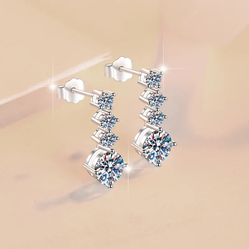 Pair of silver earrings with clear gemstones on a beige background