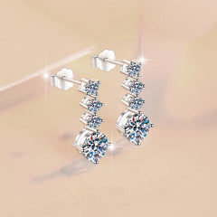 Pair of silver earrings with clear gemstones on a beige background