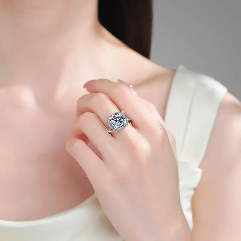 Close-up of a hand wearing a diamond ring on a neutral background