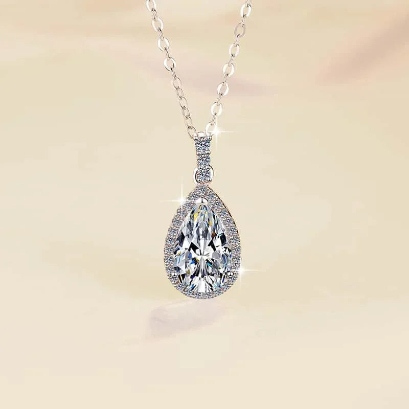 Teardrop-shaped diamond pendant on a chain against a soft beige background