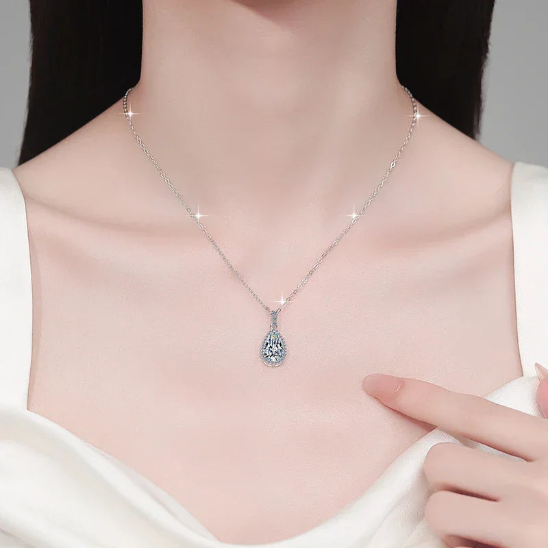 Necklace with a teardrop-shaped pendant worn by a person, with a hand pointing to it.
