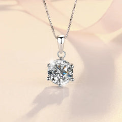 Silver necklace with a round diamond pendant on a soft beige background