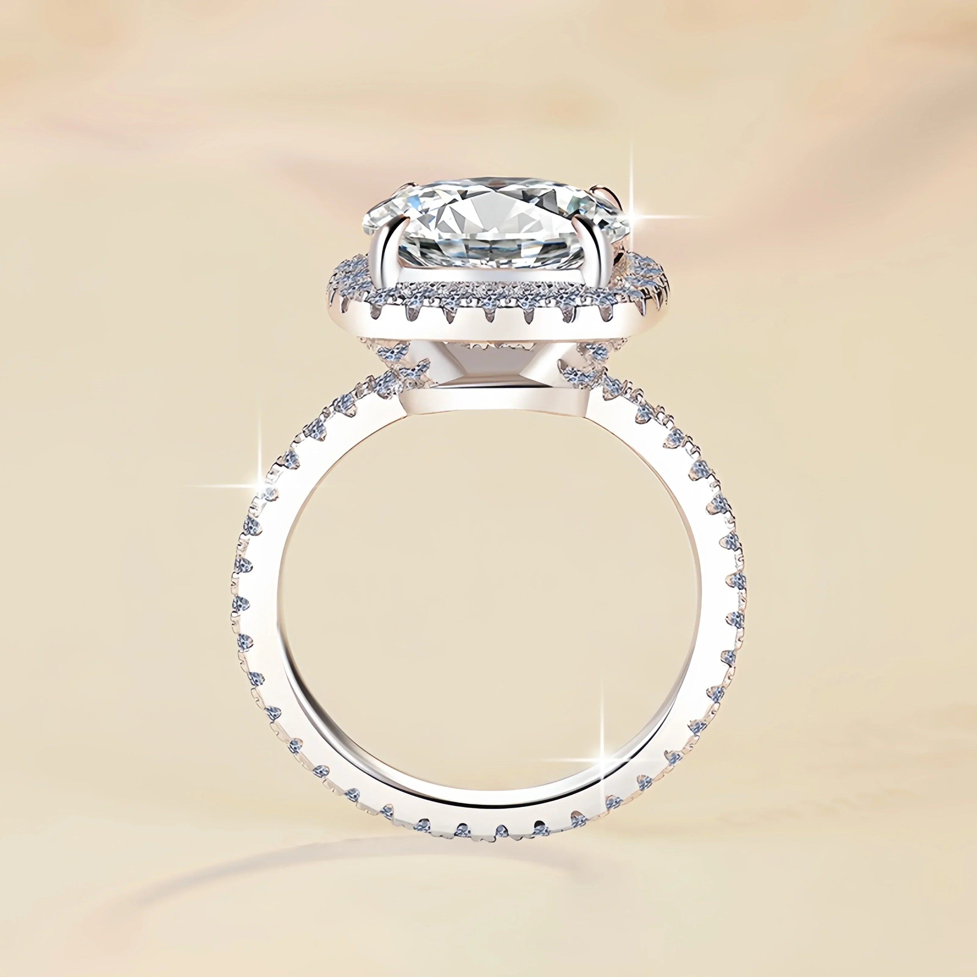 Silver ring with a large diamond and smaller diamonds on the band against a beige background