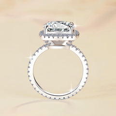 Silver ring with a large diamond and smaller diamonds on the band against a beige background