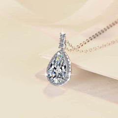 Teardrop-shaped diamond pendant on a beige background