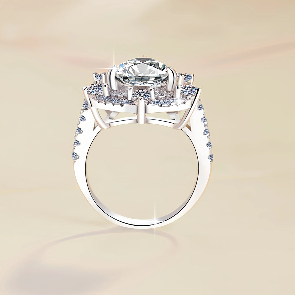 Silver ring with a large central diamond and smaller diamonds on the band against a beige background