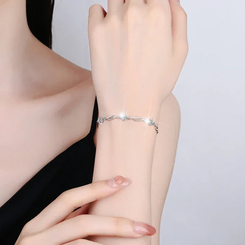 Silver bracelet on a wrist with a plain background