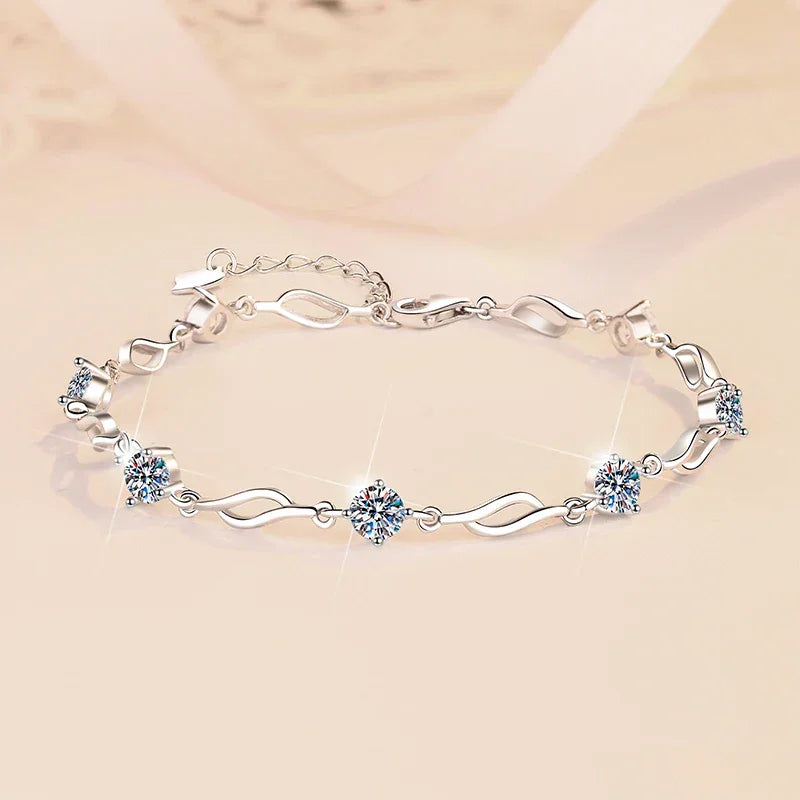 Silver bracelet with heart and flower designs on a beige background
