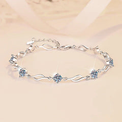 Silver bracelet with heart and flower designs on a beige background
